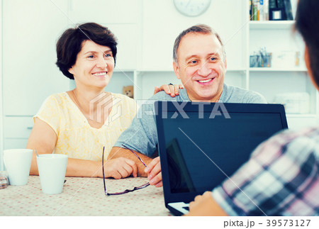 Mature couple looking at woman showing laptop 39573127