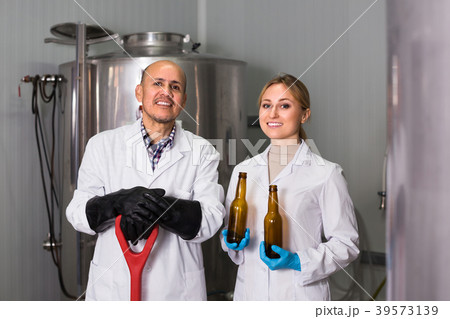 Man and woman working on modern brewery. Man and woman working on modern brewery. 39573139