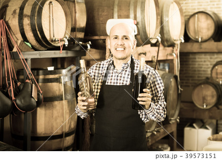 Happy mature man working on cork bottle device Happy mature man working on cork bottle device 39573151