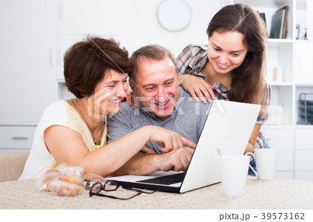 Daughter showing documents on laptop to her parents 39573162