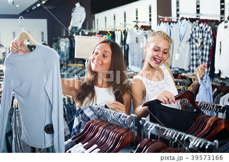 two girls buying tops in clothes store . two girls buying tops in clothes store . 39573166