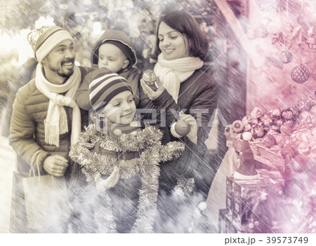 Parents with kids choosing X-mas decorations in market Parents with kids choosing X-mas decorations in market 39573749