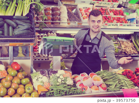 attractive male seller showing assortment of grocery shop attractive male seller showing assortment of grocery shop 39573750