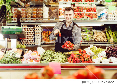 professional male seller showing assortment of grocery shop 39574022