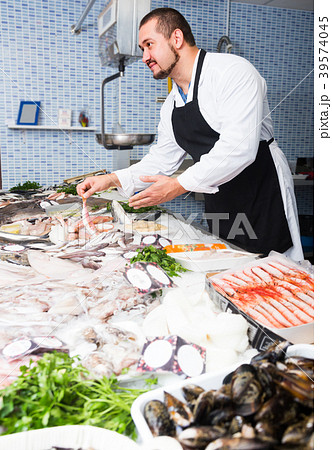 Man behind counter holding fish Man behind counter holding fish 39574045
