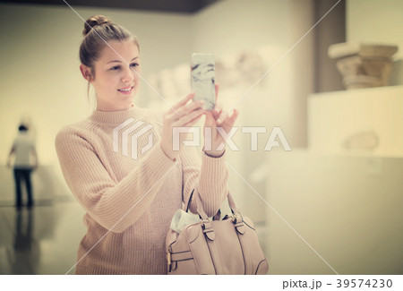 Positive female holding mobile in the historical museum Positive female holding mobile in the historical museum 39574230