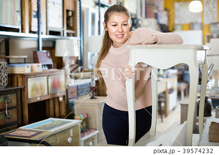 Positive woman customer touching dressing table in furniture shopping room Positive woman customer touching dressing table in furniture shopping room 39574232