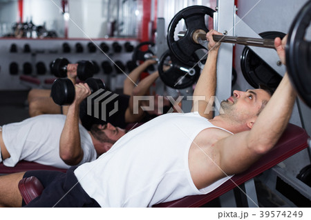 Man during training with barbell in gym Man during training with barbell in gym 39574249