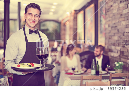 Smiling waiter with serving tray in restaurant 39574286