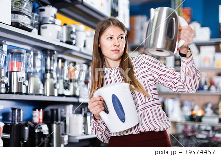 Young attractive woman choosing kettle in household appliances store Young attractive woman choosing kettle in household appliances store 39574457