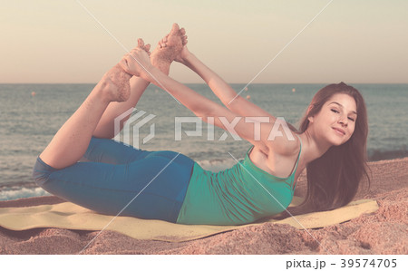 Smiling young woman in blue T-shirt is practicing stretching Smiling young woman in blue T-shirt is practicing stretching 39574705