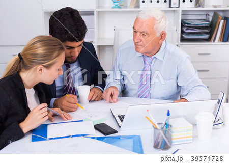 Employees are writing financial reports and discussing with mature boss 39574728