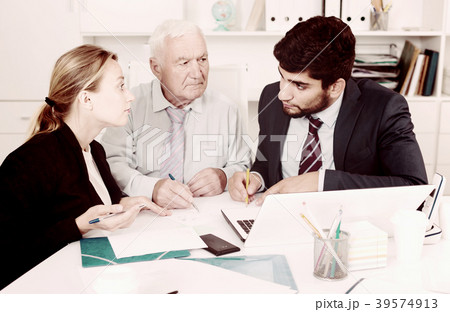 Employees are writing financial reports and discussing with mature boss 39574913