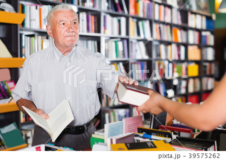 Mature male customer is purchasing new book Mature male customer is purchasing new book 39575262