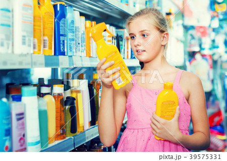 concentrated teenager girl choosing bottles of sun protection indoors concentrated teenager girl choosing bottles of sun protection indoors 39575331