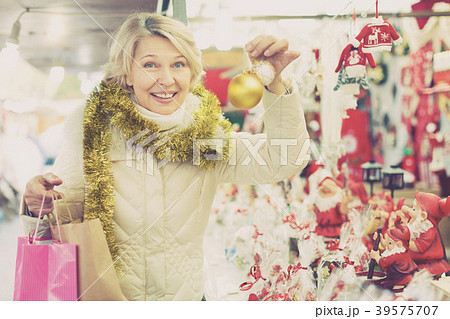 Happy mature woman in tinsel with Christmas toys at fair Happy mature woman in tinsel with Christmas toys at fair 39575707