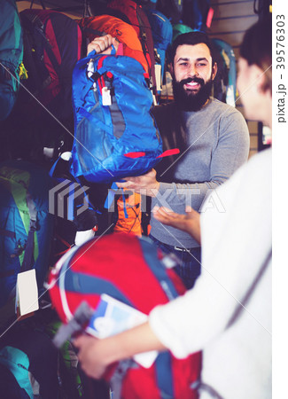 cheerful young pair examining rucksacks in sports equipment store cheerful young pair examining rucksacks in sports equipment store 39576303