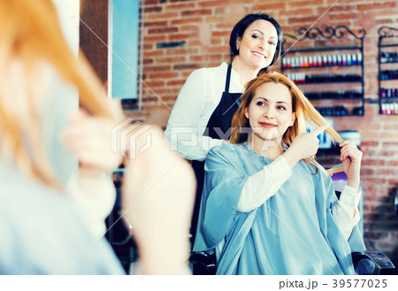 Woman points to master in hairdress salon right hair length for haircut 39577025