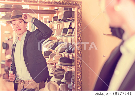 customer try on brim hat and looking in mirror at dressing room customer try on brim hat and looking in mirror at dressing room 39577241
