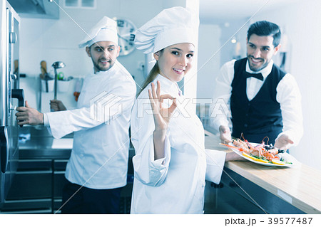 Smiling woman chef approving dish in kitchen of fish restaurant before serving guests Smiling woman chef approving dish in kitchen of fish restaurant before serving guests 39577487