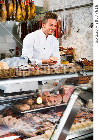 Assistant in grocery shop greeting customers Assistant in grocery shop greeting customers 39577616