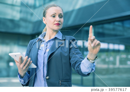 Female with digital tablet looking on finger in the city Female with digital tablet looking on finger in the city 39577617
