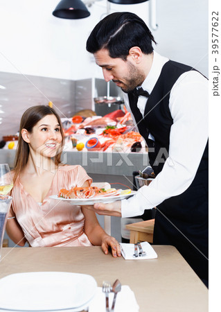Attractive girl served by waiter, enjoying dinner in fish restaurant 39577622