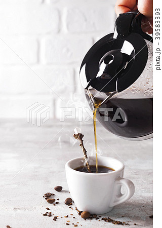 Pouring a cup of hot coffee into the glass for 39583393