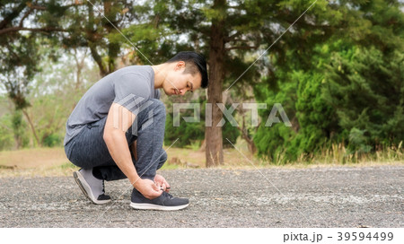 Men knelt down to do up his shoelaces 39594499