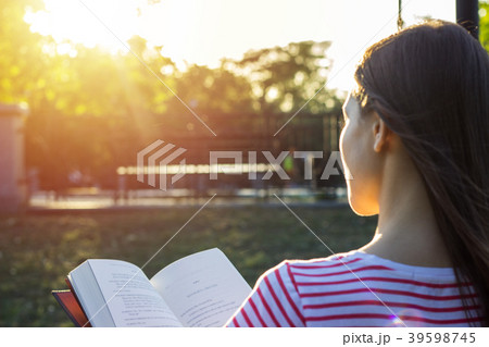 woman sitting on a bench reading a book in sunset woman sitting on a bench reading a book in sunset 39598745