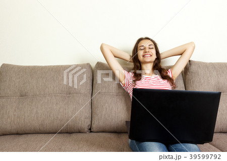 Relaxed woman lying on sofa with laptop on pillow Relaxed woman lying on sofa with laptop on pillow 39599792