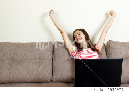 Young woman sitting on a sofa with her laptop Young woman sitting on a sofa with her laptop 39599794