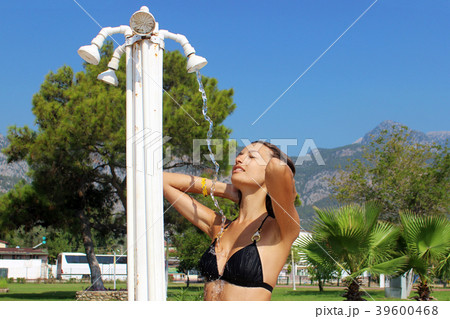 Sensous slim woman taking shower at the beach Sensous slim woman taking shower at the beach 39600468