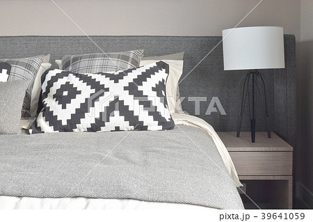 Graphic pattern pillows on bed with reading lamp 39641059