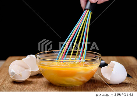 Mixing egg with a colorful whisk eggshells 39641242