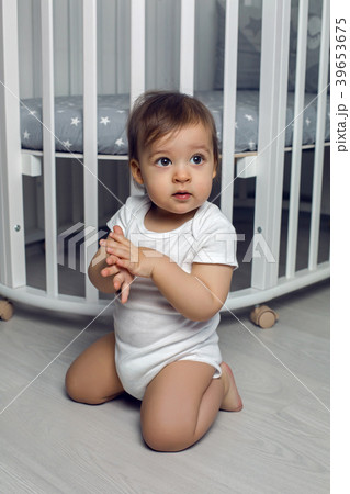 child in white clothing one year sitting on the 39653675