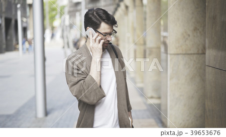 A young man dressed in casual clothes talking on 39653676