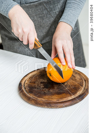 Woman cuts orange on board close Woman cuts orange on board close 39680404