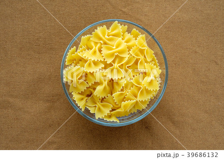 farfalle macaroni pasta in a glass bowl on a brown farfalle macaroni pasta in a glass bowl on a brown 39686132
