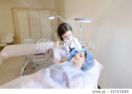 Female person getting permanent makeup at cabinet 39703880