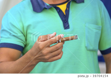 Cuban cigar in a man's hand against a light shirt 39704154