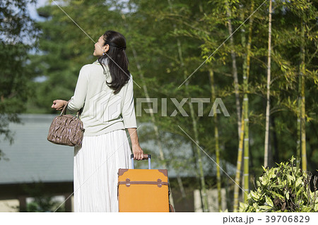 スーツケースを持つ中年女性の後姿の写真素材