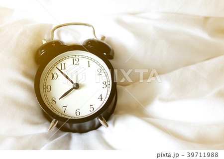 vintage black alarm clock at 8:00 am on white bed. vintage black alarm clock at 8:00 am on white bed. 39711988
