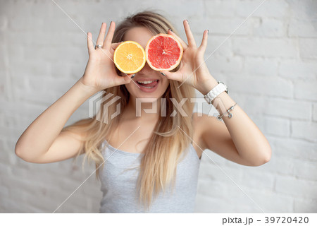 Happy smiling Woman holding two halves of citrus 39720420