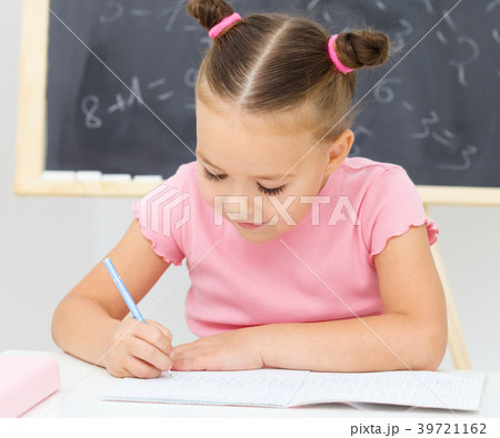 Little girl is writing using a pen Little girl is writing using a pen 39721162
