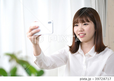 部屋でスマートフォンを見る女性 39728717