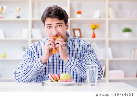 Man having dilemma between healthy food and bread 39734251