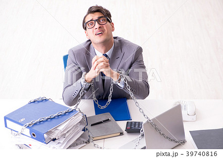 Busy employee chained to his office desk 39740816