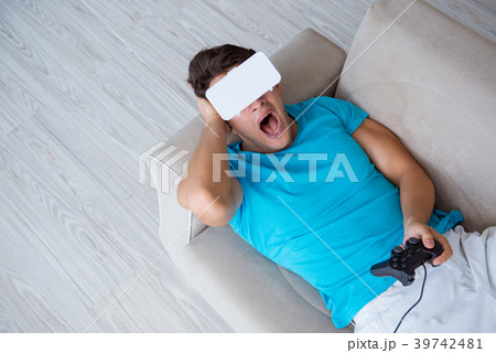 Young man wearing VR glasses relaxing on couch 39742481