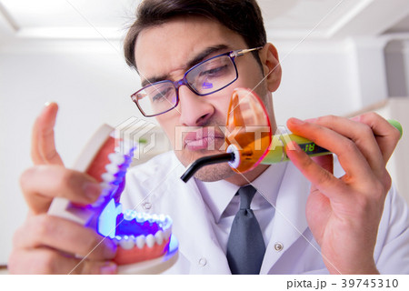 Funny dentist with curing light in medical concept 39745310